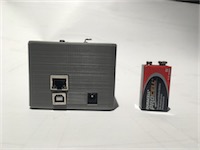 View of the side of the device, with battery for scale